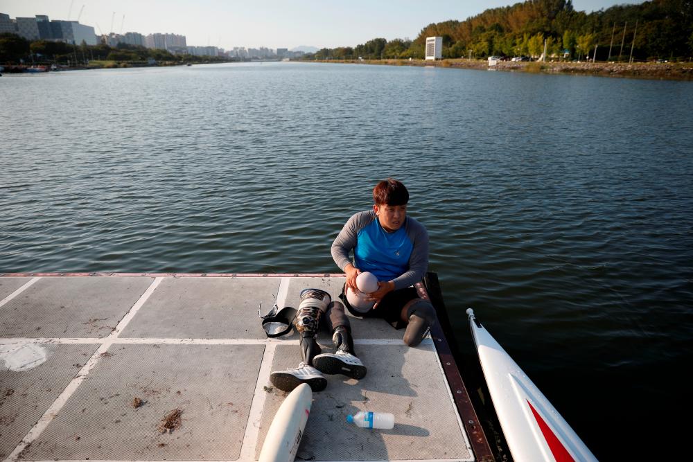 Former South Korean Army sergeant, first class, Ha Jae-hun, who lost both his legs in 2015 when he stepped on a North Korean landmine while on a patrol in the demilitarized zone (DMZ), puts on his artificial legs after a practice session at Misari Rowing Stadium in Hanam, South Korea Sept 24, 2019. — Reuters