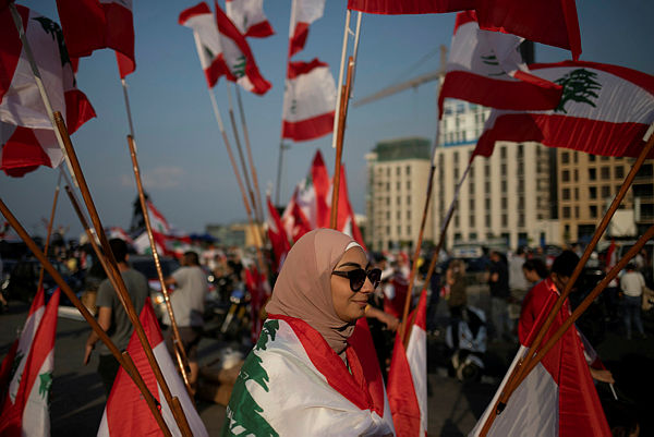 A demonstrator walks past Lebanese national flags during an anti-government protest in downtown Beirut, Lebanon October 22, 2019. — Reuters