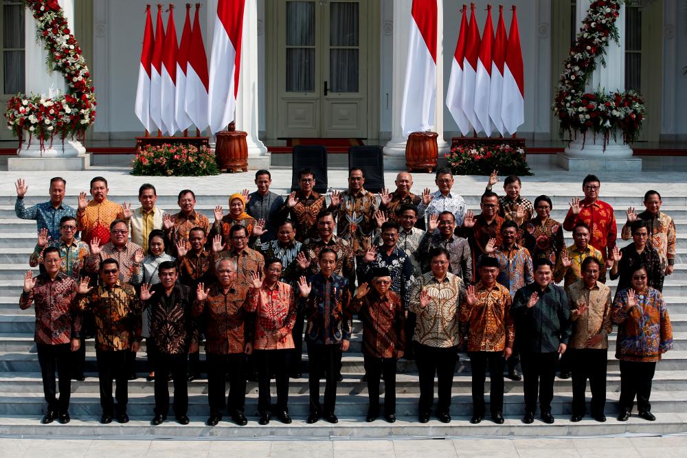 Indonesian President Joko Widodo, Vice President Ma'ruf Amin, and newly appointed cabinet ministers wave as they pose for photographers before the inauguration of new cabinet ministers for Widodo's second term, at the Presidential Palace in Jakarta, Oct 23, 2019. — Reuters