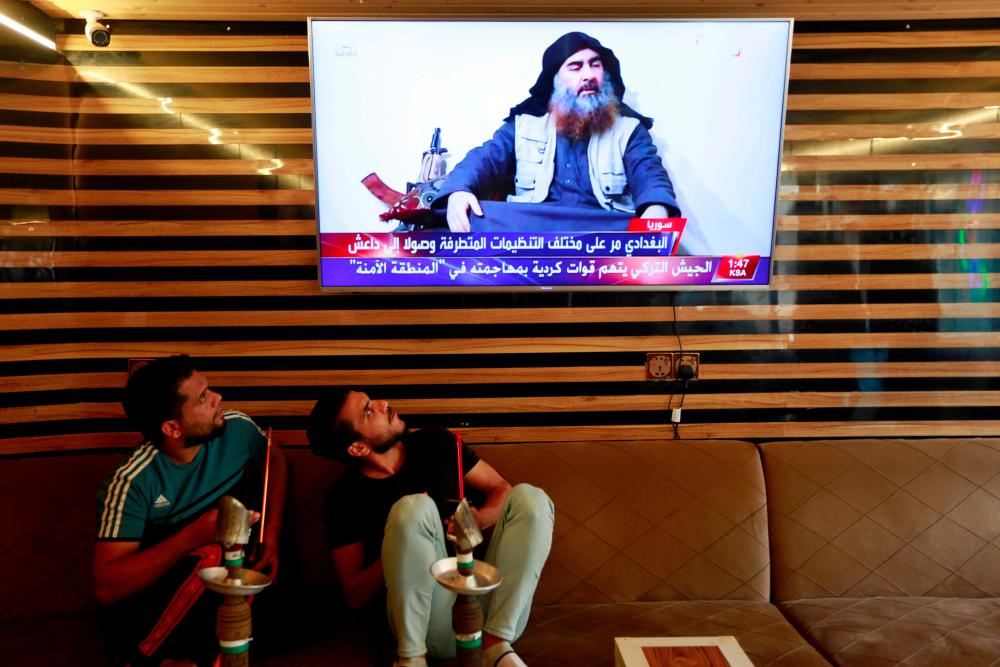Iraqi youth watch the news of Islamic State leader Abu Bakr al-Baghdadi death, in Najaf, Iraq, Oct 27, 2019. — Reuters