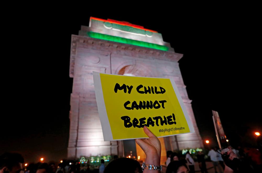 File photo taken on Nov 5 shows a protester holding a placard in front of the India Gate during a protest demanding government to take immediate steps to control air pollution in New Delhi, India. — Reuters
