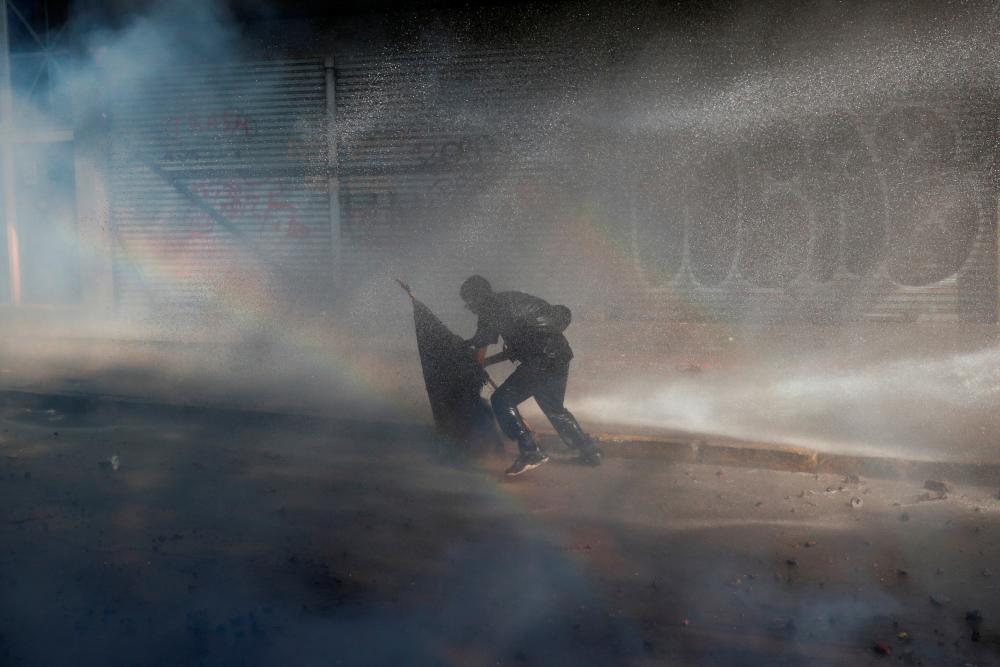 A demonstrator is sprayed by security forces with a water cannon during a protest against Chile's government in Santiago, Chile, Nov 14. — Reuters