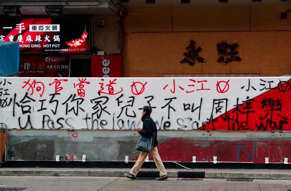 A man walks past graffiti sprayed by protesters on a wall in Hong Kong, China, Dec 9. — Reuters