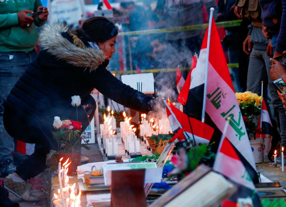 An Iraqi demonstrator lights up a candle for people killed at an anti-government protest in Baghdad, Iraq, Dec 10. — Reuters