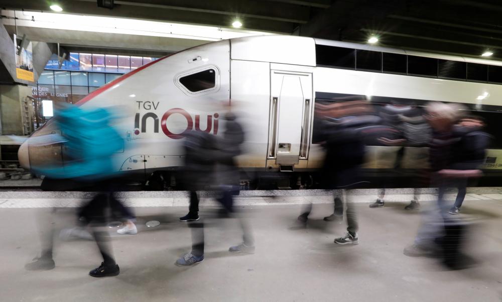 Passengers walk past a TGV train at Gare Montparnasse train station during a strike by all unions of French SNCF workers and the Paris transport network (RATP), as France faces its eleventh consecutive day of strikes against French government's pensions reform plans, in Paris, France, Dec 15. — Reuters