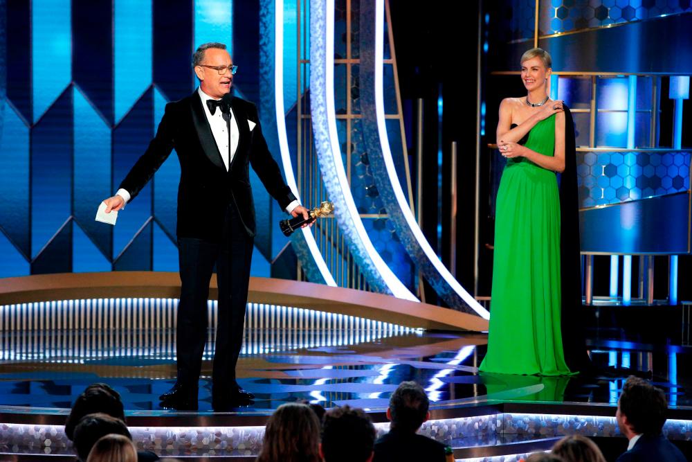 7th Golden Globe Awards - Show - Beverly Hills, California, U.S., January 5, 2020 - Tom Hanks accepts the Cecil B. DeMille Award as Charlize Theron looks on. Paul Drinkwater/NBC Universal/Handout via REUTERS