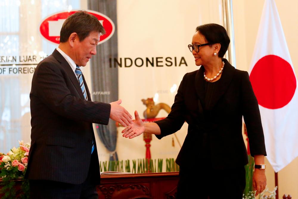 Japanese Foreign Minister Toshimitsu Motegi shakes hands with Indonesia's Foreign Minister Retno Marsudi during a meeting in Jakarta, Indonesia, Jan 10. — Reuters