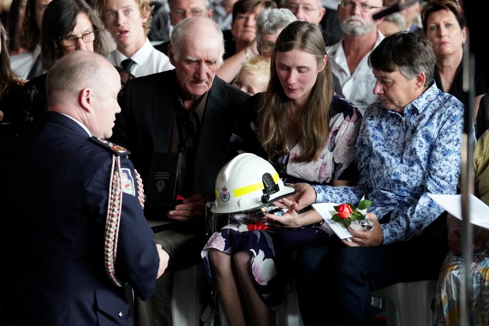 NSW Fire Commissioner Shane Fitzsimmons presents the helmet of NSW Rural Fire Service (RFS) volunteer firefighter Samuel McPaul to his widow, Megan during the funeral of McPaul at Holbrook Sports Stadium in Albury, NSW, Australia, Jan 17. — Reuters