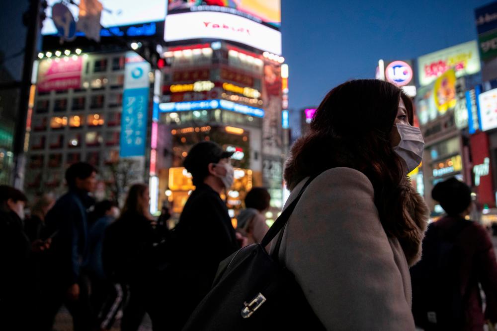 Following the outbreak of the coronavirus in Japan, a woman wearing a protective mask is seen at the scramble crossing in Shibuya shopping district in Tokyo, Mar 3. — Reuters