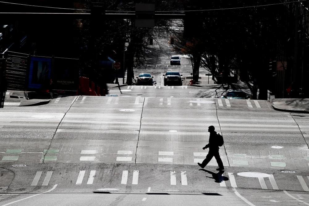 A pedestrian crosses a street, amid the coronavirus (COVID-19) outbreak, in downtown Seattle, Washington, U.S., March 16, 2020.