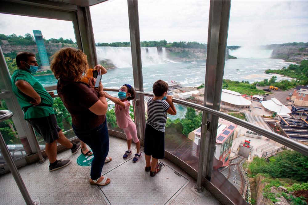 $!Canadian tourists take photos as they travel down to the Hornblower tourist boat, limited under Ontario’s rules to just six passengers amid the spread of the coronavirus disease (COVID-19), in Niagara Falls, Ontario, Canada July 21, 2020. REUTERS/Carlos Osorio