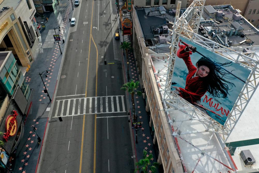 FILE PHOTO: A poster of the Walt Disney Studios’ “Mulan” movie, which was going to be released on March 27, towers over an empty Hollywood Boulevard during the global outbreak of coronavirus disease (COVID-19), in Hollywood, Los Angeles, California, U.S., March 31, 2020. REUTERS/Lucy Nicholson/File Photo