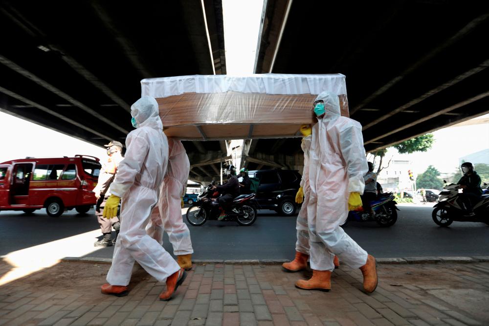 FILE PHOTO: Government workers wearing protective suits carry a mock-up of a coffin of a coronavirus disease (COVID-19) victim on the sidewalk of a main road to warn people about the dangers of the disease as the outbreak continues in Jakarta, Indonesia, August 28, 2020. REUTERS/Willy Kurniawan/File Photo