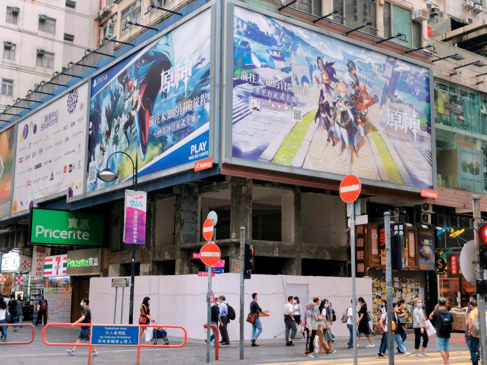 People walk below a billboard ad of fantasy game “Genshin Impact” from Shanghai-based developer Mihoyo in Hong Kong, China October 20, 2020. REUTERS/Pei Li