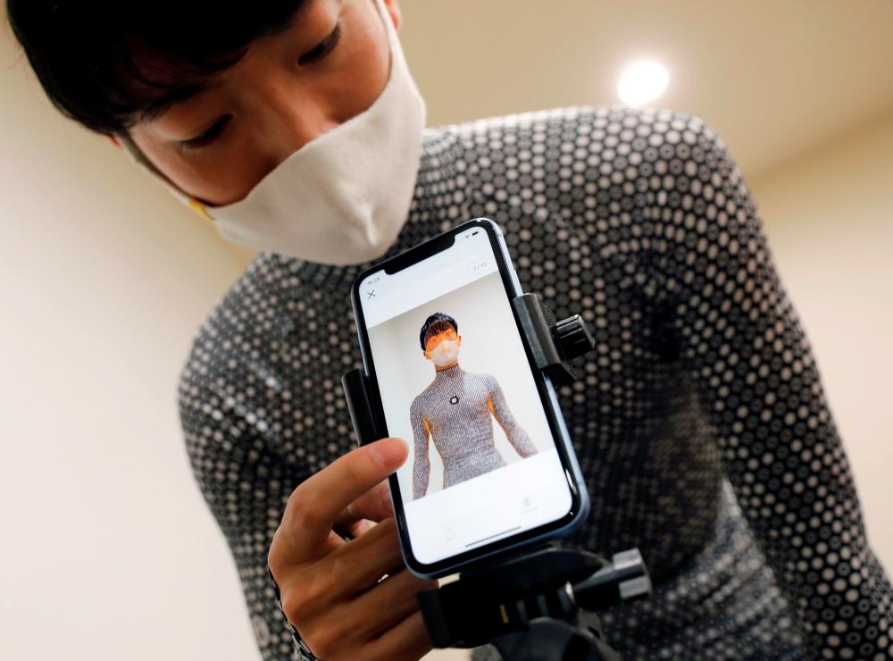 $!An employee of online fashion retailer Zozo Inc. demonstrates the company’s Zozosuit 2, a 3D body measurement suit, at their Tokyo office in Tokyo, Japan October 30, 2020. Picture taken October 30, 2020. REUTERS/Issei Kato