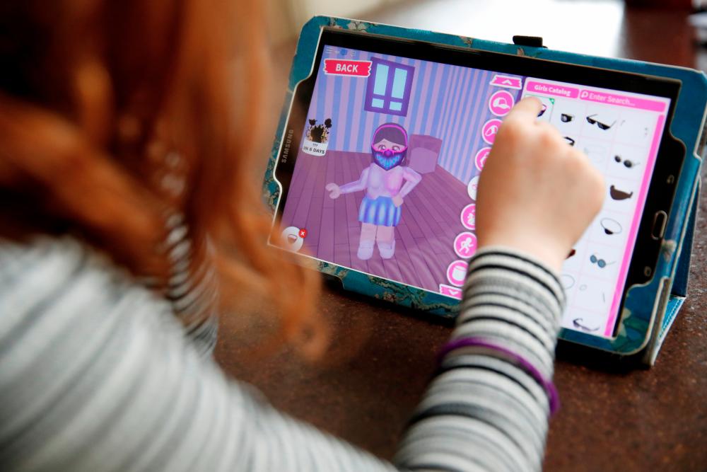 FILE PHOTO: Alice Wilkinson (7) adds a face mask to her character on the game ‘Roblox’ at her home in Manchester, as the spread of the coronavirus disease (COVID-19) continues, Manchester, Britain, April 5, 2020. REUTERS/Phil Noble/File Photo
