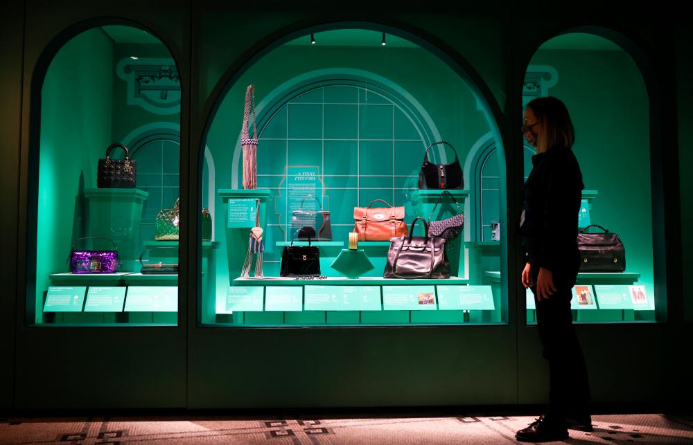 A museum employee poses next to a display of handbags that form part of the ‘Bags: Inside Out’ exhibition at the Victoria and Albert Museum in London, Britain, December 8, 2020. Picture taken December 8, 2020. REUTERS/Henry Nicholls