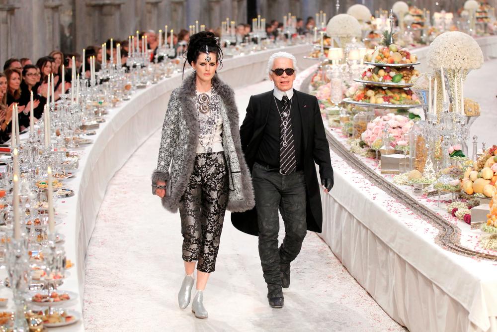 $!FILE PHOTO: British model Stella Tennant walks with designer Karl Lagerfeld during the Metiers D’Art Show for Chanel fashion house in Paris December 6, 2011. The show, which exists since 2003, is an homage to Chanel workshops. REUTERS/Benoit Tessier