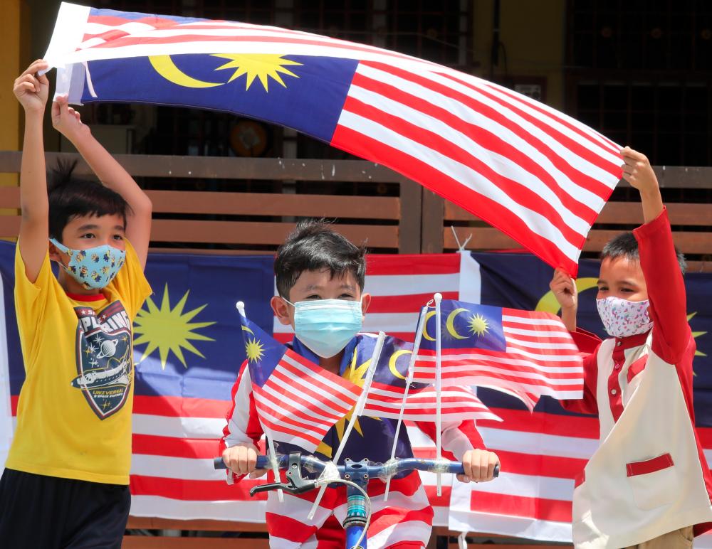 $!PATRIOTIC SPIRIT ... Haifal Yusri (centre) with friends Ridhuan Hakimi (right) and Abdul Rahman waving the Jalur Gemilang near their homes in Kepala Batas, Penang yesterday ahead of Merdeka Day on Aug 31. The theme for this year’s celebrations is ‘Malaysia Cares’. – MASRY CHE ANI/THE SUN