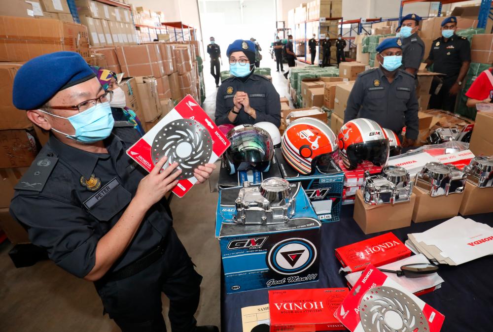 $!FAKE ITEMS ... Penang Ministry of Domestic Trade and Consumer Affairs chief enforcement officer Peter J. Berinus Agang showing some of the seized imitation motorcycle accessories, spare parts and helmets worth RM340,500 at a premises in Taman Gemilang, Bukit Mertajam on Wednesday. – MASRY CHE ANI/THESUN