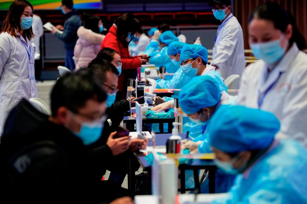 People fill forms before receiving a dose of a coronavirus disease (COVID-19) vaccine at a vaccination site, during a government-organised visit, following the coronavirus disease (COVID-19) outbreak, in Shanghai, China January 19, 2021. REUTERS/Aly Song