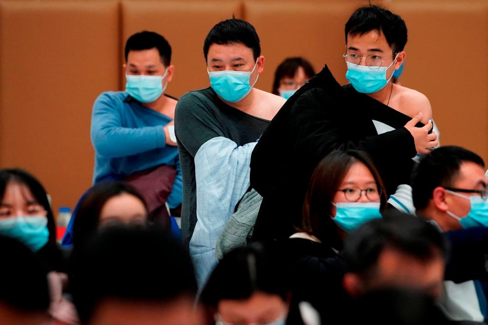 FILE PHOTO: People stand at a vaccination site after receiving a dose of a coronavirus disease (COVID-19) vaccine, during a government-organised visit, following the coronavirus disease (COVID-19) outbreak, in Shanghai, China January 19, 2021. REUTERS/Aly Song/File Photo