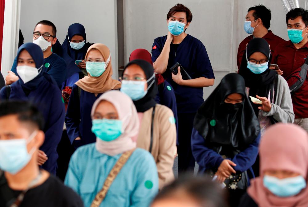 Indonesian medical workers stand in line as they queue to receive the Sinovac’s vaccine for the coronavirus disease (COVID-19) during a mass vaccination at the Istora Senayan stadium in Jakarta, Indonesia, February 4, 2021. REUTERS/Willy Kurniawan