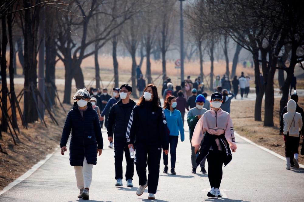 People wearing masks take a walk amid the coronavirus disease (COVID-19) pandemic at a Hanriver Park in Seoul, South Korea, February 21, 2021. - Reuters