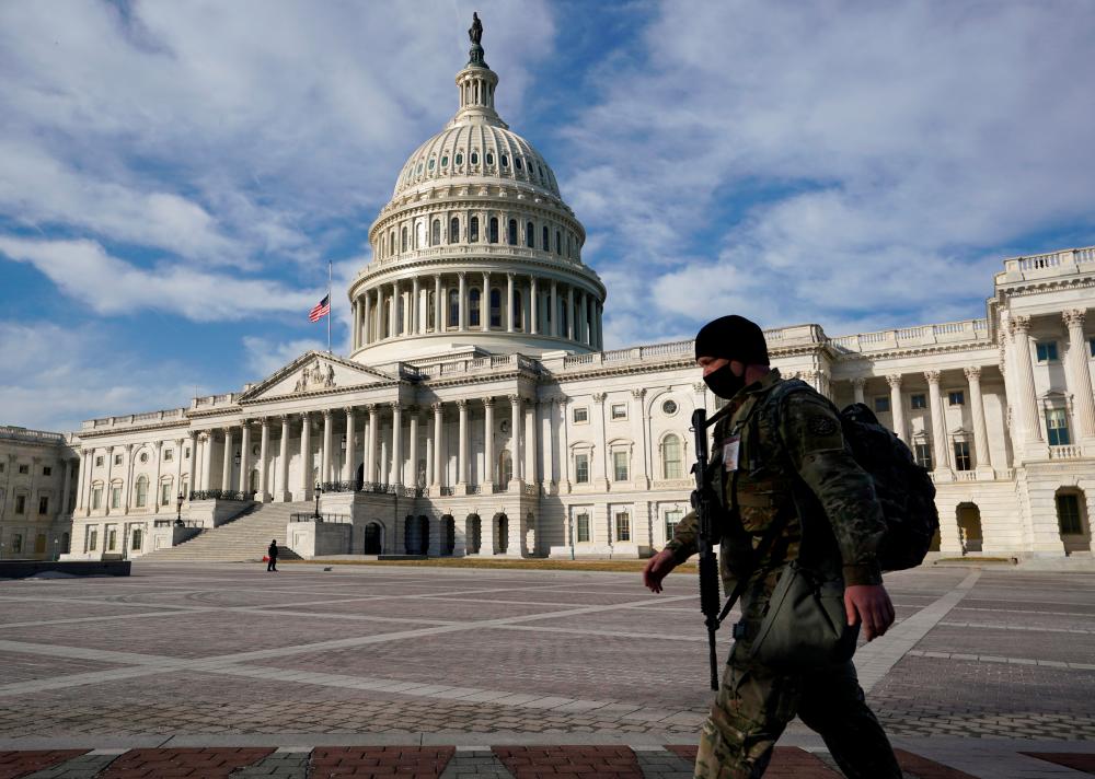 FILE PHOTO: A National Guardsman passes the U.S. Capitol in Washington, U.S., February 26, 2021. REUTERS/Kevin Lamarque/File Photo