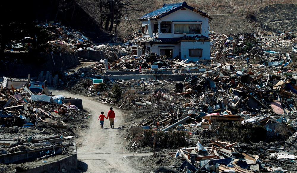 FILE PHOTO: People walk at an area that was damaged by the March 11 earthquake and tsunami, in Miyako, Iwate prefecture, April 5, 2011. - Reuters