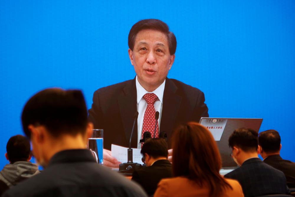 National People’s Congress (NPC) spokesman Zhang Yesui is seen on a screen during a news conference held via video link ahead of the annual parliament meeting in Beijing, China March 4, 2021. - Reuters