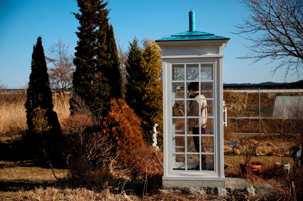 A woman from Ofunato who lost her junior high school classmates in the March 11, 2011 earthquake and tsunami, calls her late friends inside Kaze-no-Denwa (the phone of the wind), a phone booth set up for people to call their deceased loved ones, at Bell Gardia Kujira-yama, ahead of the 10th anniversary of the disaster, in Otsuchi town, Iwate Prefecture, northern Japan February 28, 2021. - Reuters