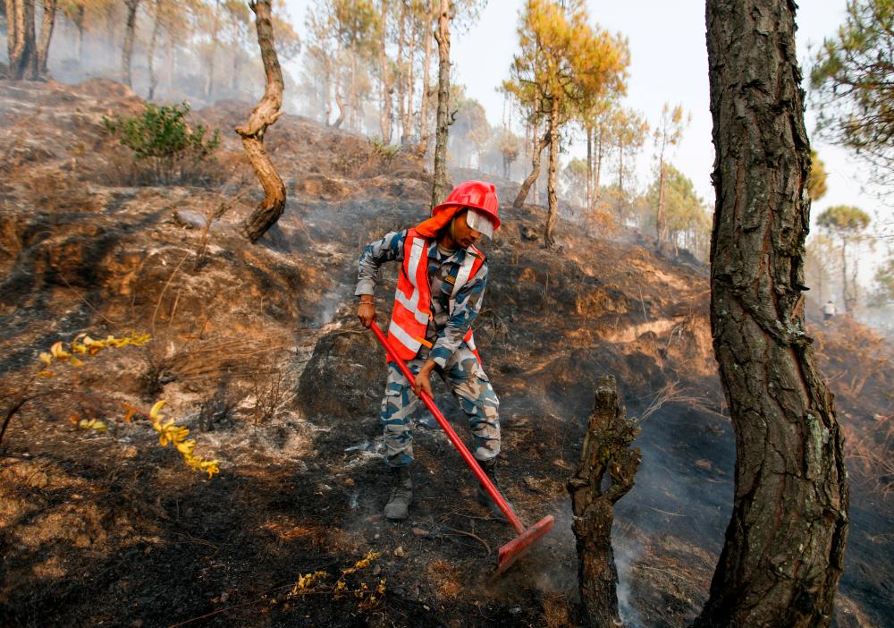 A member of the Armed Police Force works to control a forest fire at Shivapuri National Park overlooking Kathmandu, as forest fires have raged many areas in Nepal contributing to worst air quality in the bowl shaped Kathmandu, Nepal April 11, 2021. –Reuters