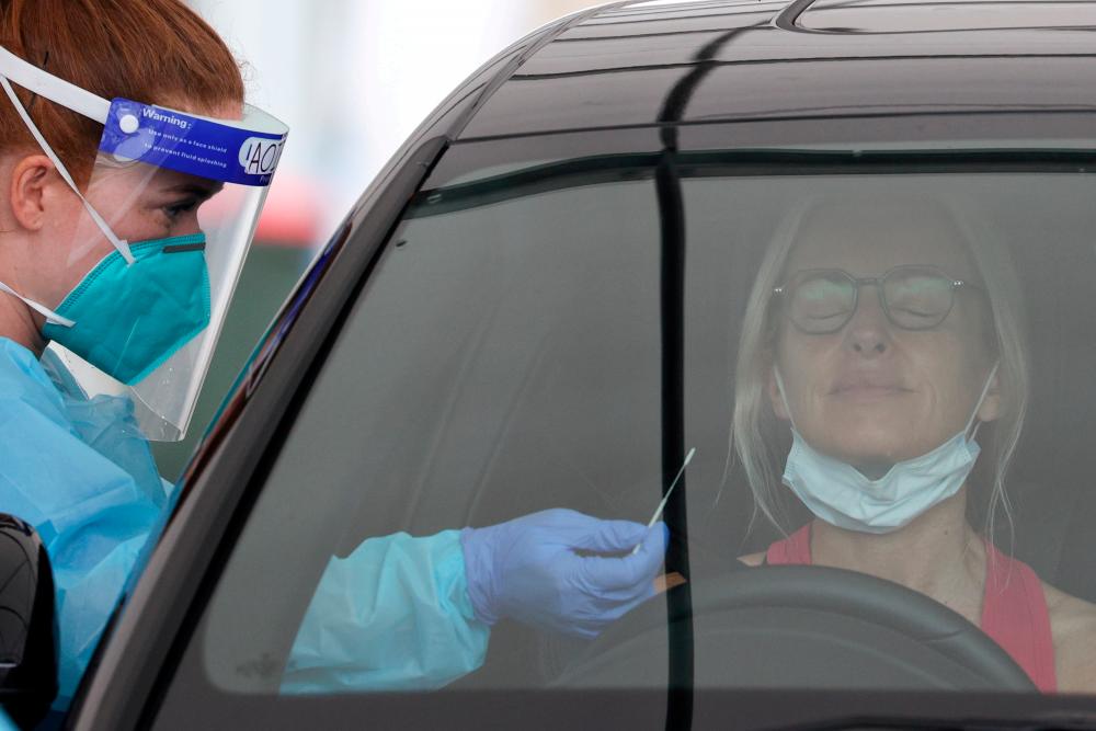 FILE PHOTO: A medical worker swabs a member of the public at the Bondi Beach drive-through coronavirus disease (COVID-19) testing centre as the city experiences an outbreak in Sydney, Australia, December 21, 2020. –Reuters