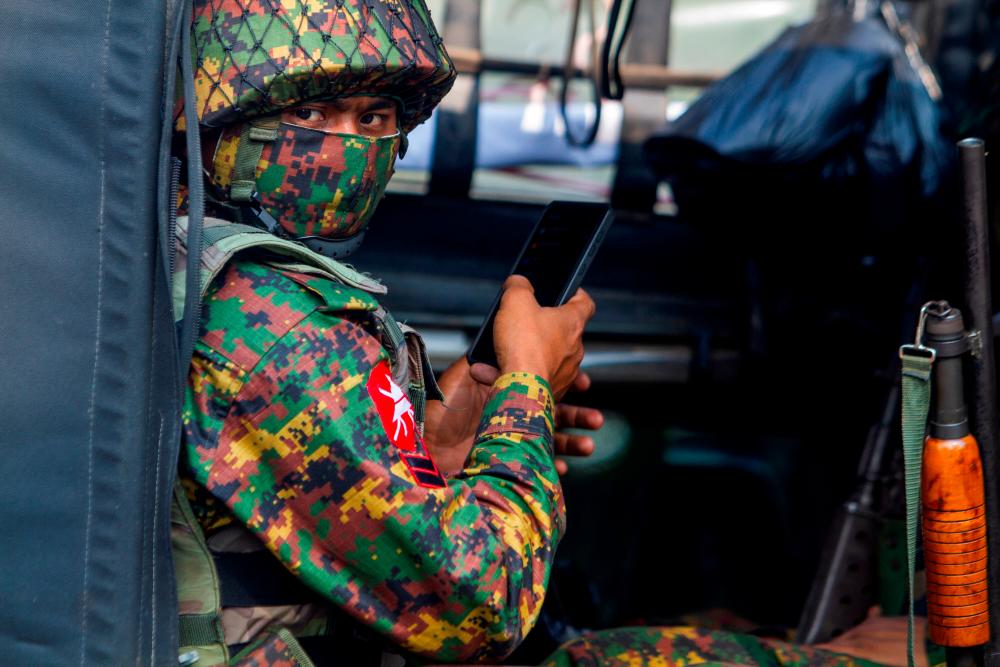 FILE PHOTO: A soldier uses a mobile phone as he sit inside a military vehicle outside Myanmar's Central Bank during a protest against the military coup, in Yangon, Myanmar, February 15, 2021. – Reuters