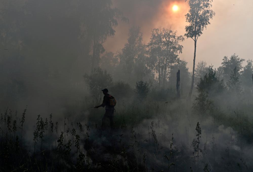 FILE PHOTO: A specialist of Russian Federal Agency for Forestry works to put out a forest fire outside the village of Basly in Omsk Region, Russia August 11, 2020. - Reuters
