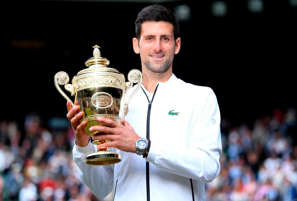 FILE PHOTO: Serbia’s Novak Djokovic poses with the trophy as he celebrates winning the final against Switzerland’s Roger Federer on July 14, 2019. – REUTERSPIX