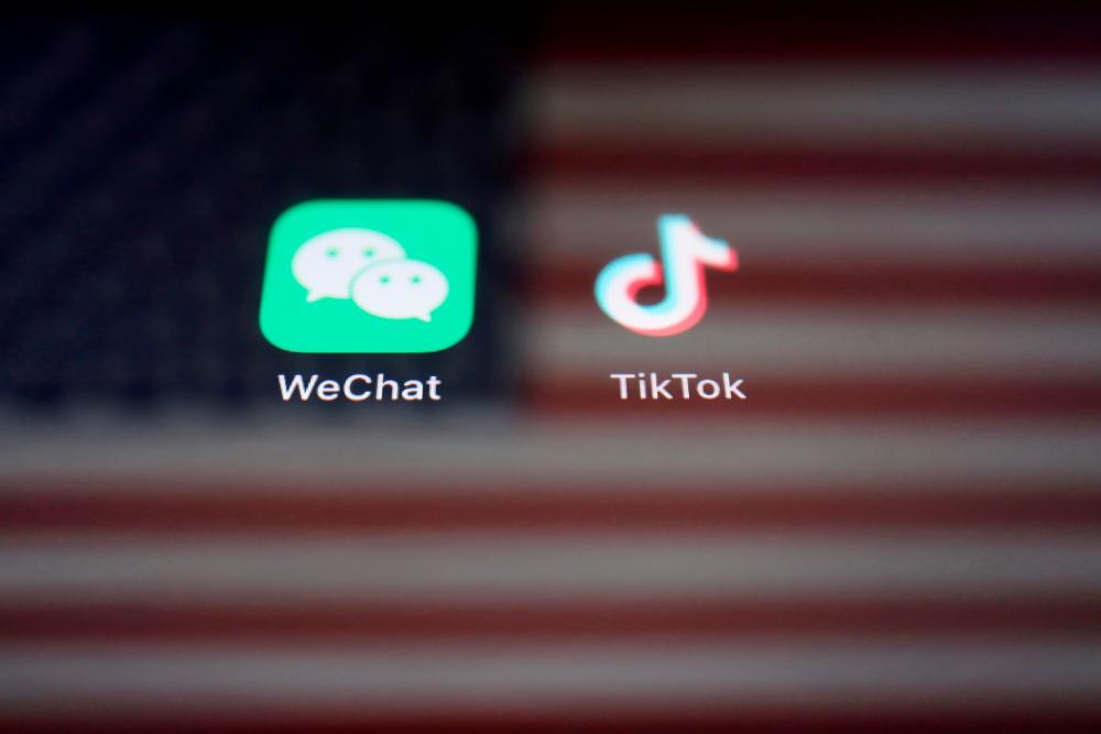 FILE PHOTO: A reflection of the US flag is seen on the signs of the WeChat and TikTok apps in this illustration picture taken September 19, 2020. - Reuters