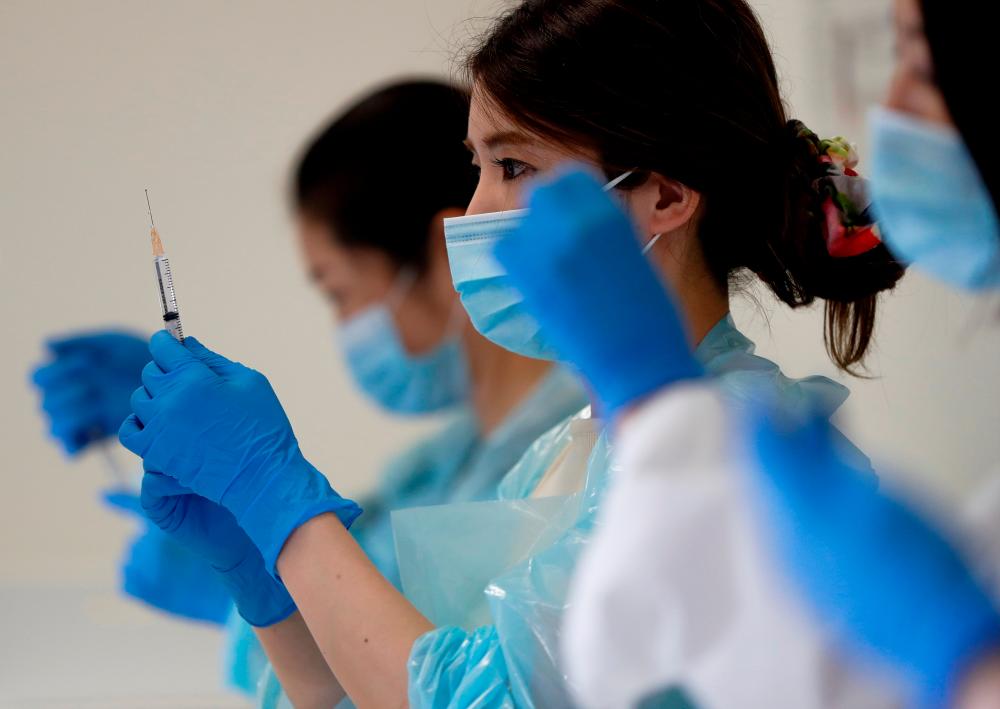 FILE PHOTO: A health worker fills a syringe with a dose of the Pfizer-BioNTech coronavirus disease (COVID-19) vaccine at the Noevir Stadium Kobe, the home venue of Japanese professional soccer club Vissel Kobe and currently acting as a large-scale COVID-19 vaccination center, in Kobe, Japan June 12, 2021. – Reuters
