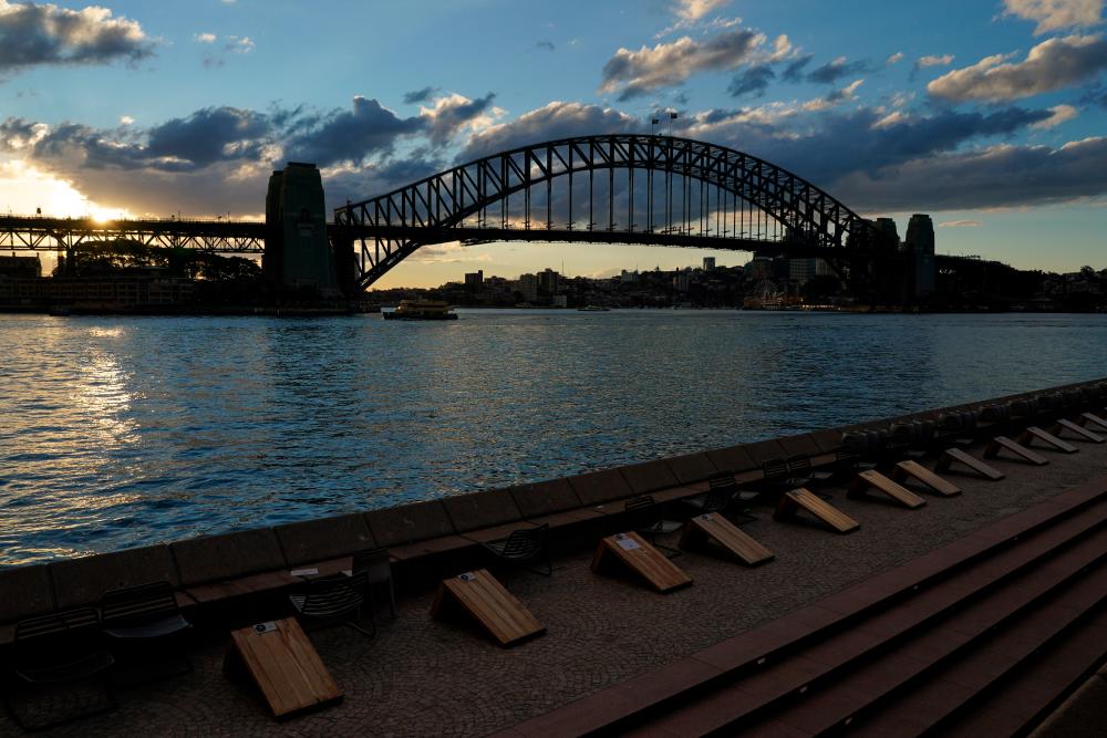 Harbour waterfront seating is devoid of people at sunset in front of the Sydney Harbour Bridge during a lockdown to curb the spread of a coronavirus disease (Covid-19) outbreak in Sydney, Australia, July 15, 2021. -Reuters