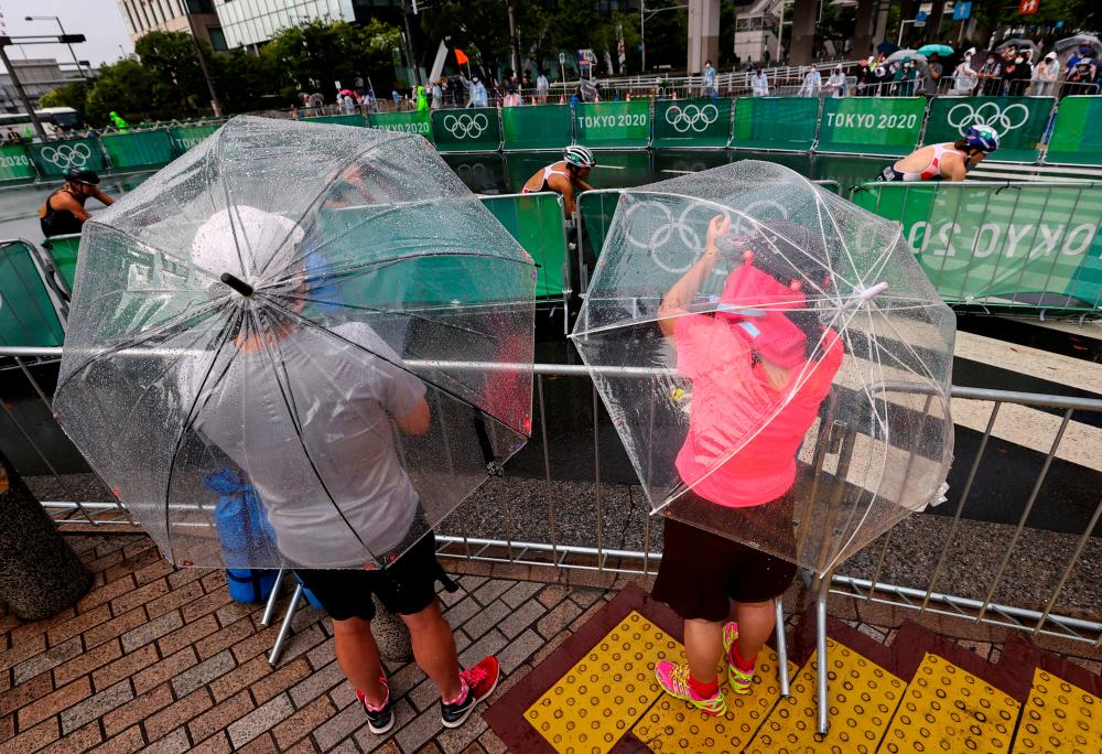 Tokyo 2020 Olympics - Triathlon - Women’s Olympic Distance - Final - Odaiba Marine Park, Tokyo, Japan July 27, 2021. Fans and residents try to catch a glimpse of the women’s triathlon event in the rain caused by tropical storm Nepartak. -Reuters