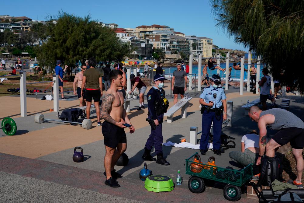 Patrolling police officers check ID information of people working out at a Bondi Beach outdoor gym area during a lockdown to curb the spread of a coronavirus disease (Covid-19) outbreak in Sydney, Australia, July 27, 2021. -Reuters
