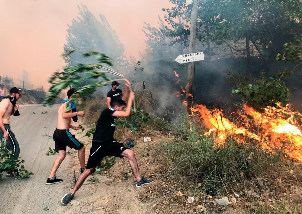 People attempt to put out a fire in the mountainous Tizi Ouzou province, east of Algiers, Algeria August 10, 2021. -Reuters