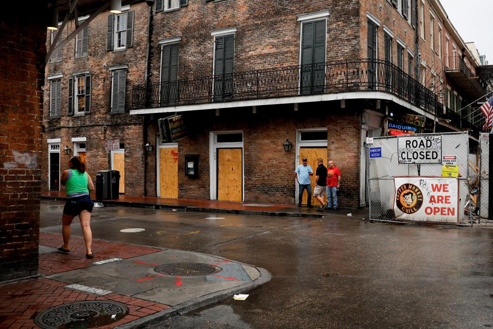 People walk past boarded up windows in Bourbon Street at the French Quarter ahead of Hurricane Ida, in New Orleans, Louisiana, US August 29, 2021. - Reuters