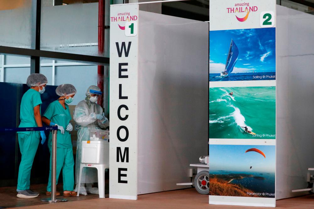 FILE PHOTO: Health workers stand at the Covid-19 swab test area at the airport as Phuket reopens to overseas tourists, allowing foreigners fully vaccinated against the coronavirus disease (Covid-19) to visit the resort island without quarantine, in Phuket, Thailand July 1, 2021. REUTERSpix
