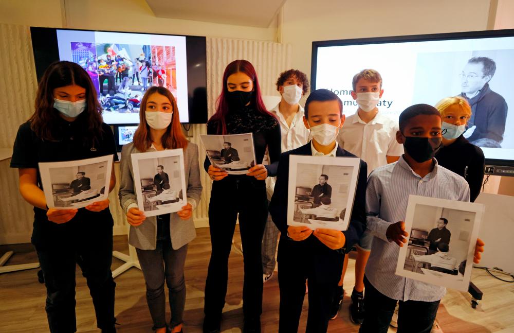 Schoolchildren hold a picture of French history teacher Samuel Paty, one year after he was beheaded outside his school in the Paris suburb of Conflans-Sainte-Honorine, during a ceremony at the Nice Education offices in Nice, France, October 15, 2021. REUTERSpix
