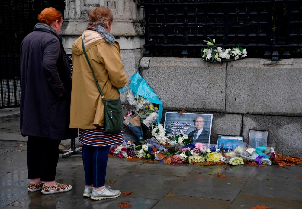 Passers-by view floral tributes to British MP David Amess, who was stabbed to death during a meeting with constituents, placed outside the Houses of Parliament, in London, Britain, October 20, 2021. REUTERSpix