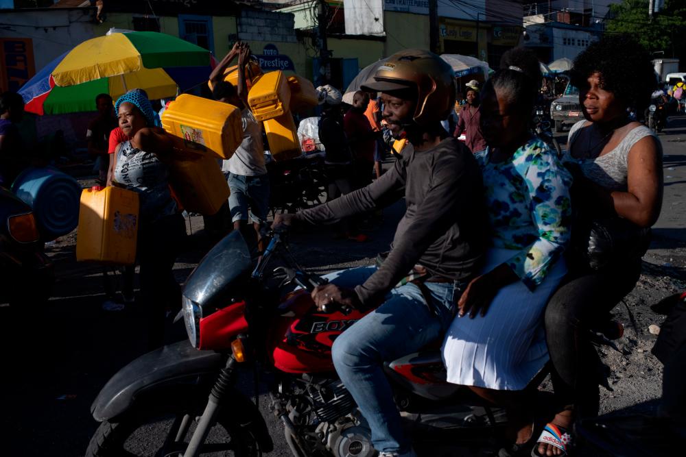 A motorbike passes by as locals carry containers, used for oil and gasoline, during fuel shortages in Port-au-Prince, Haiti October 24, 2021. REUTERSpix