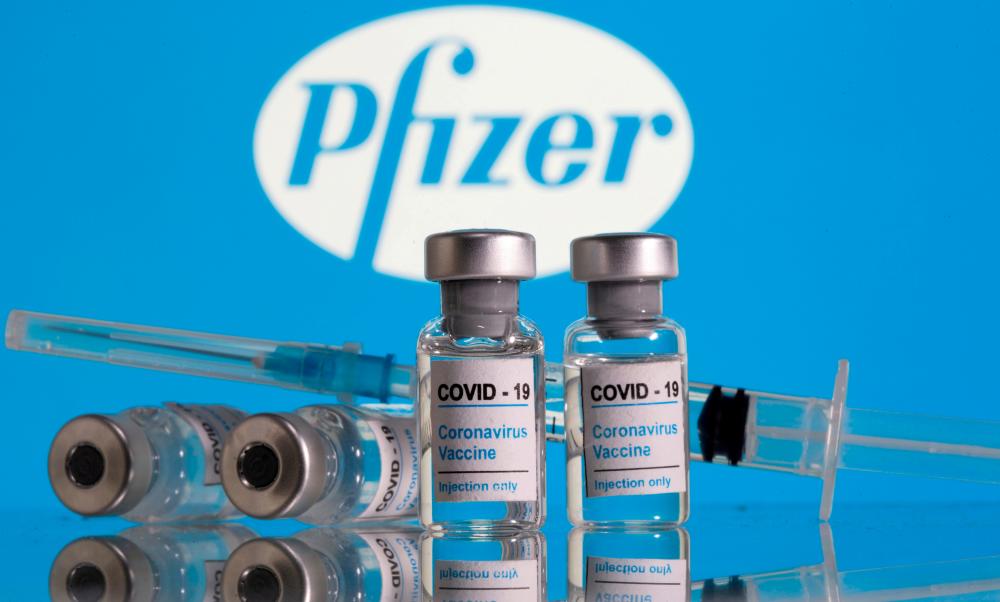 FILE PHOTO: Vials labelled COVID-19 Coronavirus Vaccine and a syringe are seen in front of the Pfizer logo in this illustration taken February 9, 2021. REUTERSpix