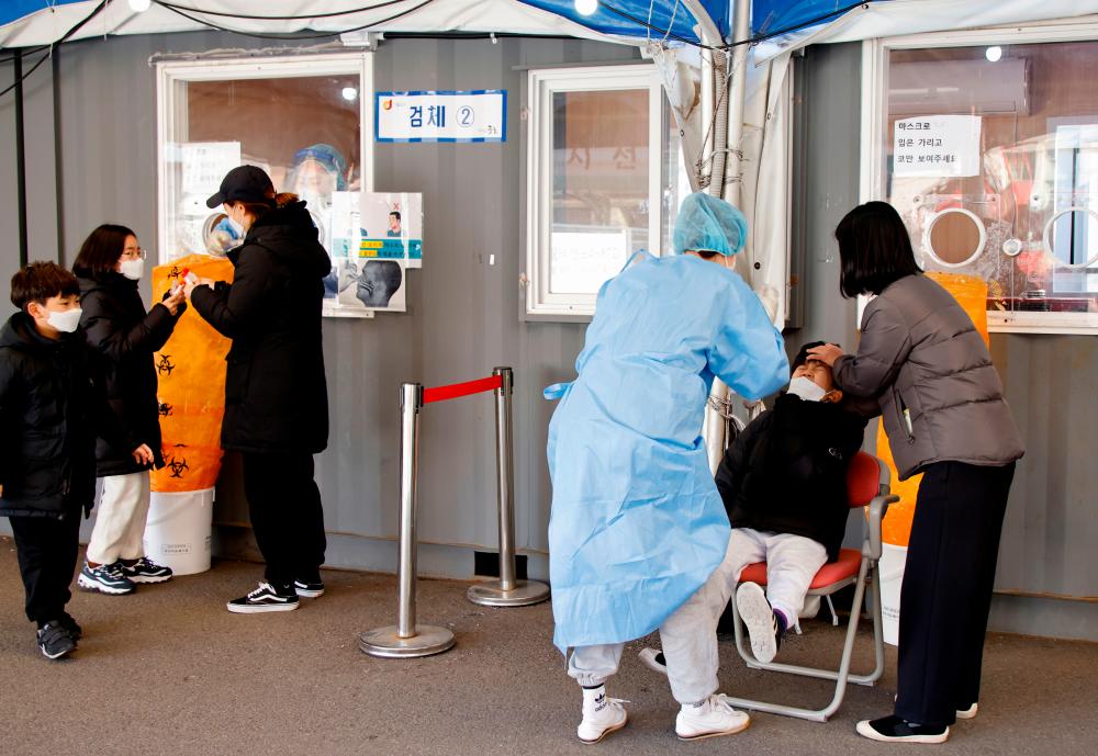 A healthcare worker collects a swab sample from a boy to test for the coronavirus disease (COVID-19), at a temporary testing site set up at a railway station, in Seoul, South Korea, December 8, 2021. REUTERSpix